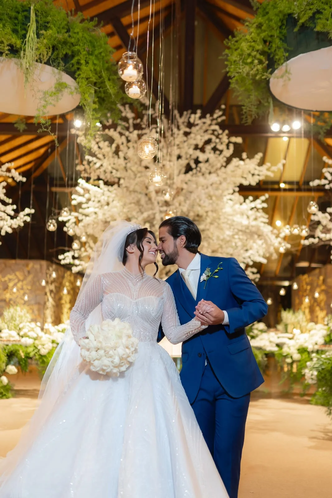 Casamento conduzido por Cris Marques — noivos sob arco de flores e luzes